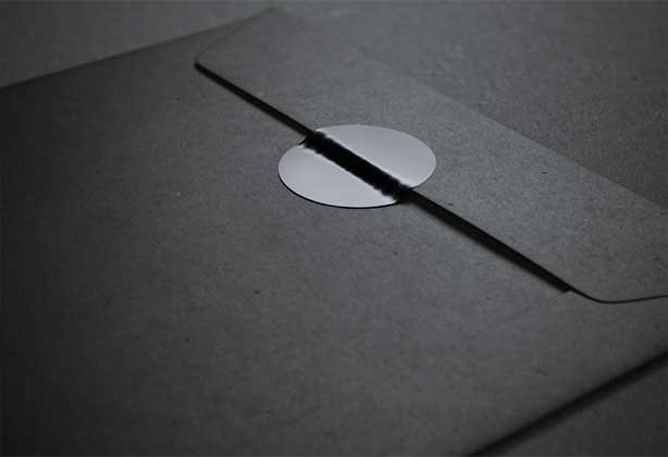 Black circular sticker on a black, matt envelope